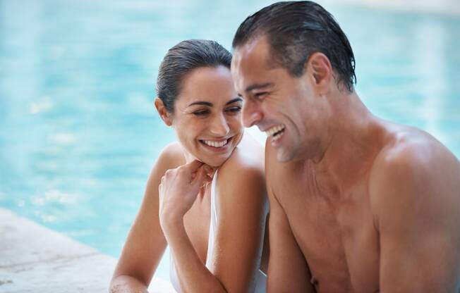 a man and woman sitting by a swimming pool