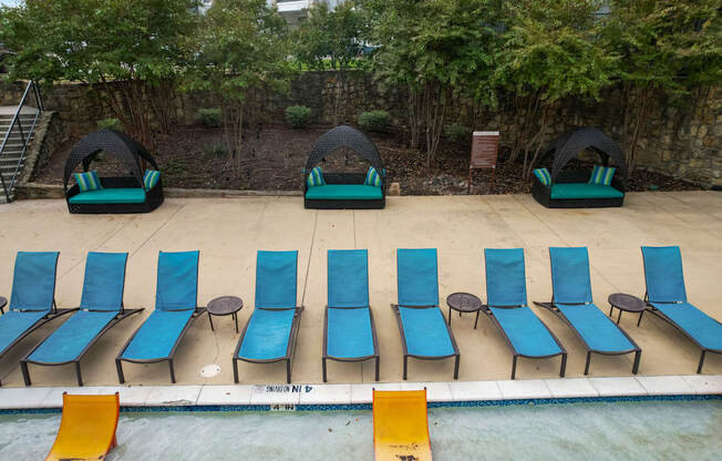 a row of blue and green chairs on the side of a pool