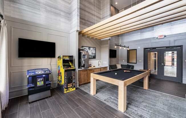 a games room with a pool table and a video game machine