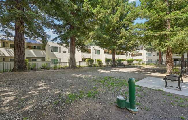 a park with trees and a bench in front of an apartment building