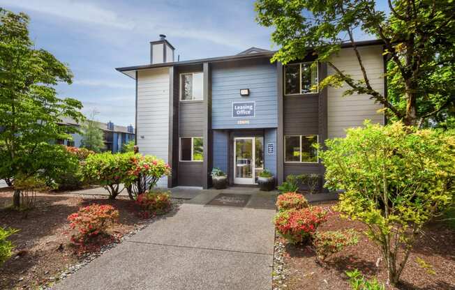 the front of a grey building with a walkway and plants at Eagles Landing Apartments, Everett, 98204