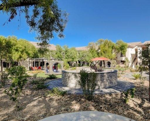 A garden with a fountain and a building in the background.