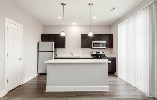 A modern kitchen with a white island and dark brown cabinets.