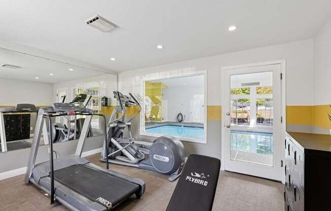 A home gym with a treadmill, weights, and exercise equipment.