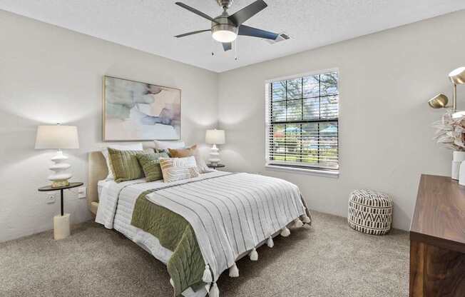 A bedroom with a large bed and a ceiling fan.