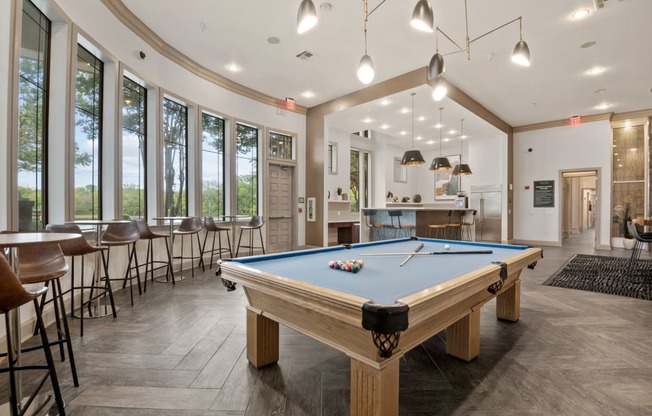 a pool table in the clubhouse of a community with tables and chairs at Mission Gate, Plano