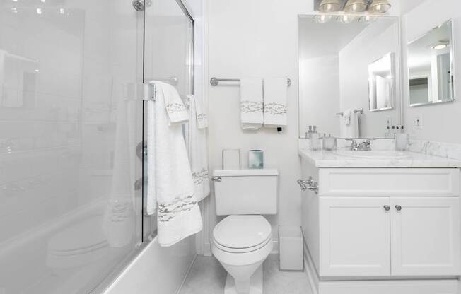 A white bathroom with a toilet, sink, and bathtub.