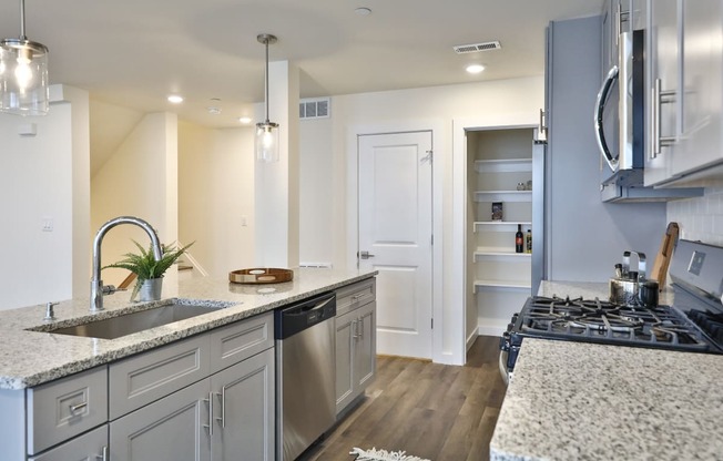 a kitchen with grey cabinets and island with pantry