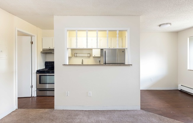 an empty living room and kitchen with a hard wood floor