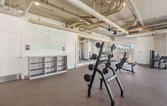 A gym with a neon sign that says "Everyday I'm muscini" on the wall.