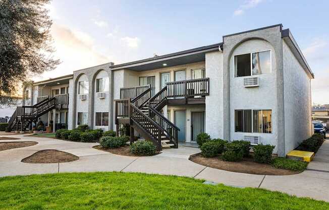 A white building with a balcony and stairs leading to the entrance.