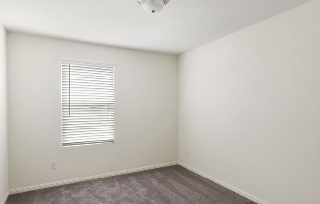 a bedroom with white walls and a window with a white blind