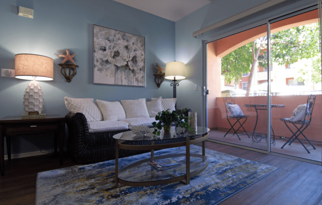 A living room with a sofa, two chairs, a table, and a painting on the wall.