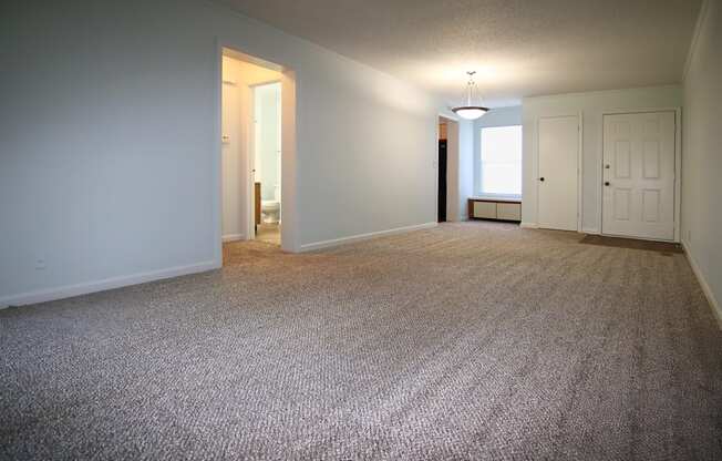 A carpeted room with a doorway leading to another room.