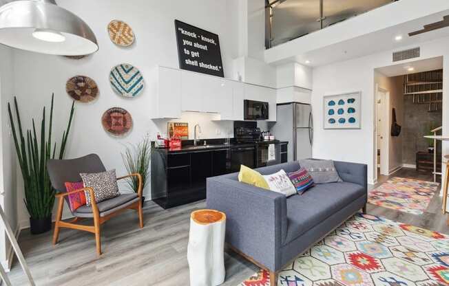 a living area with a couch chair and a kitchen in the background
