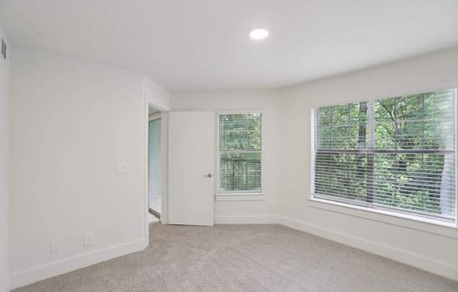 A bedroom with a carpeted floor and a window with blinds.