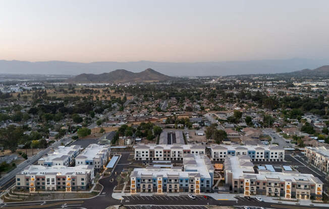 A large building complex is surrounded by a parking lot and other buildings.
