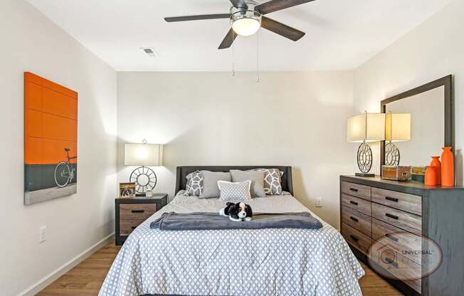 A bedroom with a bed, dresser, and ceiling fan.