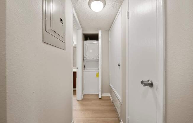 A white hallway with a refrigerator and a door on the right.