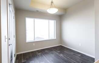 an empty living room with a large window and wood flooring