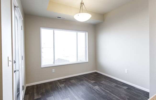 an empty living room with a large window and wood flooring