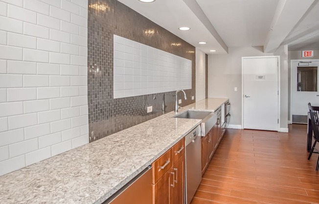 a long kitchen with granite counter tops and a sink