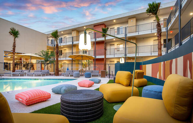 a courtyard with couches and pillows and a pool in front of a building