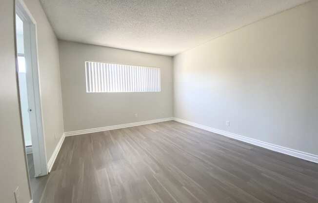 an empty living room with wooden floors and a window