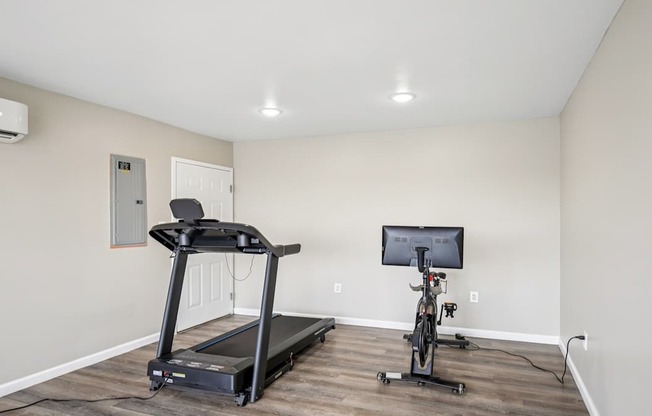 A treadmill and a stationary bike are in a room with a television.