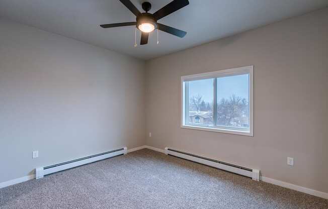 an empty room with a ceiling fan and a window. Fargo, ND Prairiewood Meadows Apartments