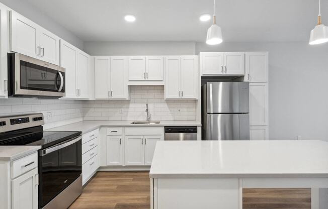 a white kitchen with stainless steel appliances and white cabinets