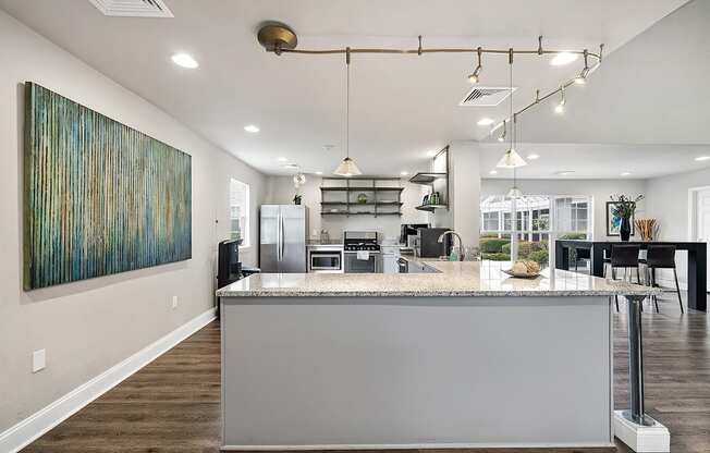 A modern kitchen with a large island and a painting on the wall.