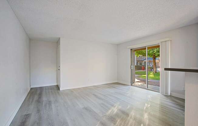 an empty living room with a sliding glass door to a patio