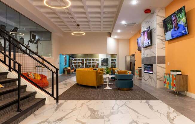 a lobby with couches and chairs and a tv on the wall