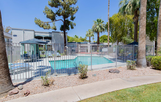 A pool surrounded by a fence and trees.