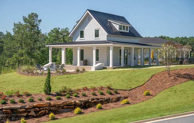 A white house with a black roof and a porch.