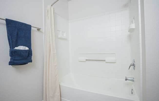 a bathroom with a shower and a blue towel on a rack