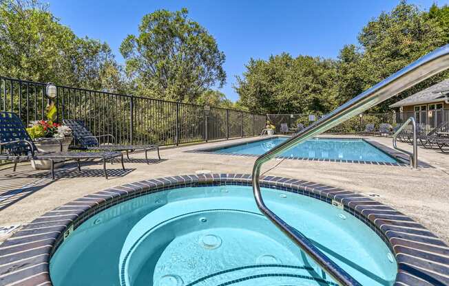 a hot tub and a pool with a fence and trees