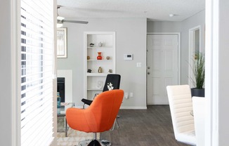 a living room with an orange chair and a wood floor