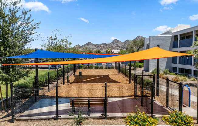 A playground with a blue and orange canopy.