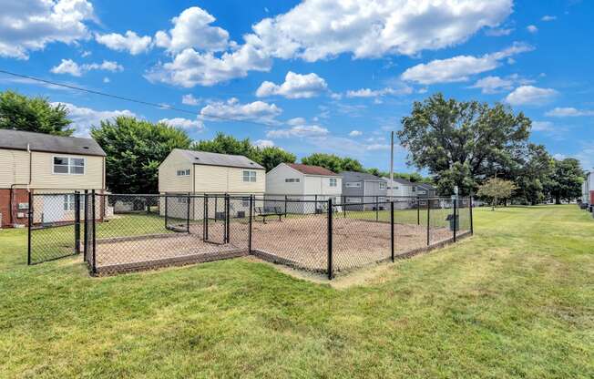 a fenced in dog park with houses in the background