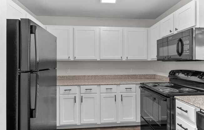 a kitchen with white cabinets and black appliances and a refrigerator