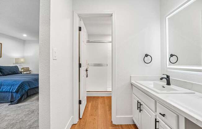 A white bathroom with a blue bed in the bedroom.