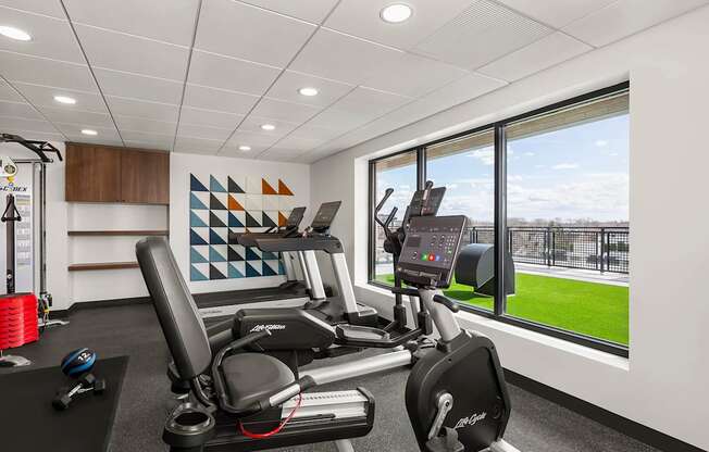 A gym with a row of treadmills and elliptical machines.