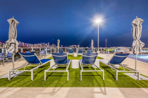 a row of chairs and tables with umbrellas near a pool