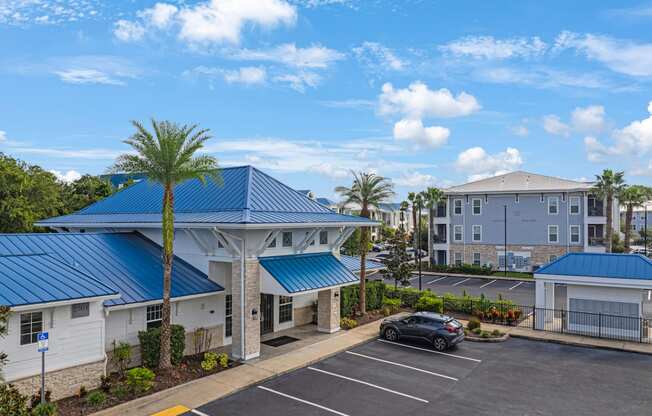 an empty parking lot in front of a building with a blue roof and palm tree