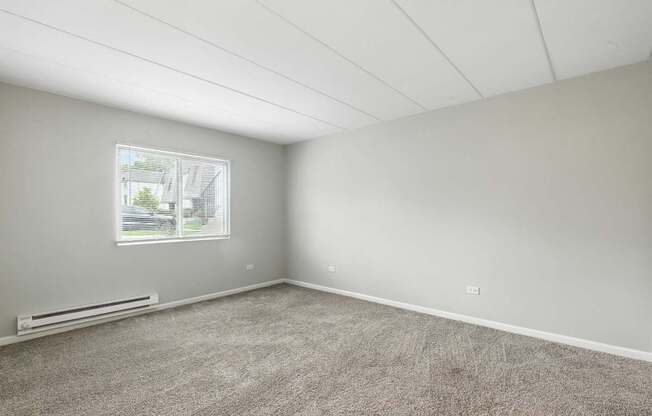 A room with a window and a carpeted floor.