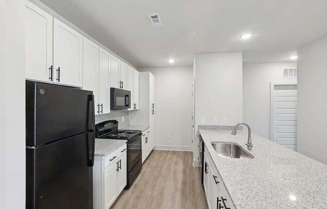 A kitchen with black appliances and white cabinets.