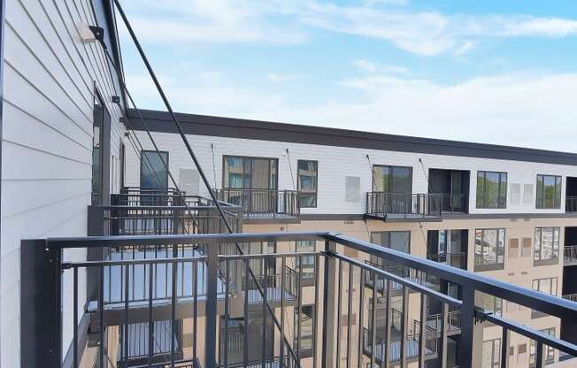 a balcony with a black railing and a white building in the background