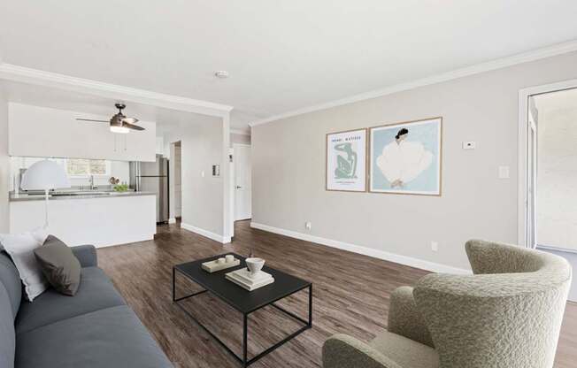 A living room with a grey couch, a black coffee table, and a beige armchair.